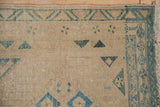Distressed texture of a vintage Persian runner showing the blue geometric border and low-pile wear.