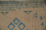 Blue geometric border and diamond motifs on the time-softened pile of a vintage Persian runner.