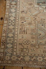 Detail of distressed vintage Karaja runner's beige field, tribal motifs, and brown patterned border with fringe.