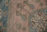 Distressed pile texture with geometric blossoms in dusty mauve, sky blue, and beige.
