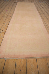 The reverse weave of a distressed Oushak runner in soft pink and sand tones.