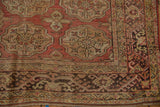 Distressed vintage Oushak rug corner, dusty rose elephant footprint medallions, hook latch border.