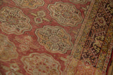 Distressed Oushak carpet with muted rose elephant footprint medallions and vine border.