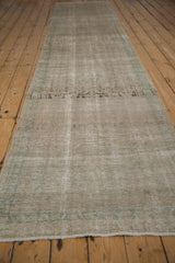 Long angle view of a distressed Hamadan runner showing its silver color variations and low, worn pile.