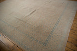 Angled view of a vintage distressed Birjand carpet with faded sand and blue Herati design.