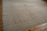Distressed vintage Birjand carpet corner with muted sand, beige, and blue Herati pattern.