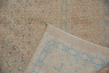 Distressed Birjand carpet with soft wool pile, sand, blue Herati motif, and visible reverse.