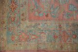 Textural vintage Lilihan carpet with faded raspberry, dusty ocean blue, and gold floral patterns.