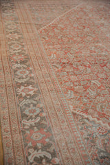 Distressed Mahal carpet's palmette border and mahi-mahi field motifs with aged terracotta and soft blue tones.