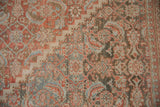 Distressed Mahal carpet close-up, faded terracotta, blue mahi-mahi Herati pattern, visible foundation.