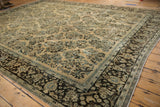 A vintage Persian carpet's dark chocolate brown border frames the ivory floral spray field.