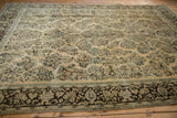 Angled view of a distressed Arak carpet's corner, showing the dark brown border and ivory floral field.