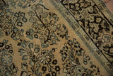 Detailed floral sprays in dusty slate blue and chocolate brown on a distressed vintage Arak carpet.