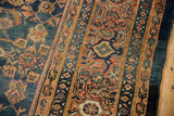 Terracotta and denim blue border motifs flanking the mahi-mahi Herati field of the Mahal carpet.