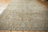 Angled view across a vintage Tabriz carpet highlighting its distressed pictorial forest design.