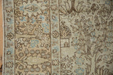 Close-up of a distressed Tabriz carpet's border showing running deer and forest motifs.