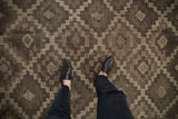 Distressed Jijim carpet underfoot, geometric lattice, diamond guls in charcoal and mauve.