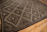 Detail of distressed Jijim carpet showing tiered checkered panels and wave-serpent border.