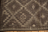 Distressed Jijim carpet detail: geometric diamond guls and wave border in charcoal and silver.