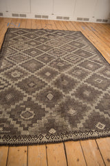Textured, distressed Jijim carpet detail: geometric checkered panels and diamond guls in charcoal and silver.