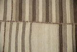 Horizontal patchwork seam on a vintage Turkish Kilim with varying brown and antique ivory stripes.