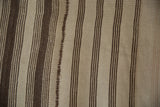 Close-up of a vintage Turkish Kilim with chocolate brown and antique ivory stripes, featuring a mended panel join.