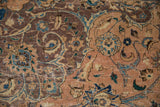 Distressed Kashan carpet detail: worn scrolling palmettes and floral motifs in peach, mauve, and blue.