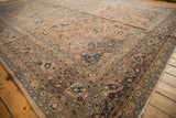 Distressed Kashan carpet corner with faded peach field, blue, brown floral patterns, pile wear.