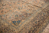 Distressed vintage Kashan carpet detail: faded peach field, brown border, blue floral motifs.