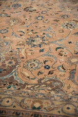 Distressed Kashan carpet detail: pale peach field, blue floral scrollwork, and visible pile wear.