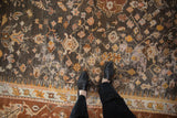 Vintage Oushak carpet field showing charcoal, saffron vinery, foundation wear, and wide border.