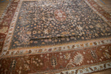 Wide banded Oushak border in chestnut and ivory, delicate vinery on charcoal field.