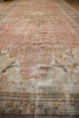 Distressed Doroksh carpet with dusty raspberry vinery, saffron buds, and visible foundation.