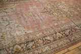 Distressed Persian Doroksh carpet, time-softened dusty raspberry field with charcoal floral border.