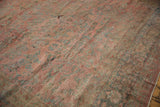 Distressed texture of the vintage Mahal carpet, revealing faded red and dusty teal floral blossoms.