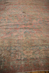 Textured view of worn floral patterns in time-softened reds and dusty teal on the distressed Mahal carpet.