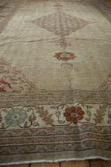 A low perspective view of a distressed Tabriz carpet, highlighting the even wear across its ivory field.