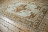 Angled view of a vintage Oushak rug showing its distressed, low pile in soft neutral tones.