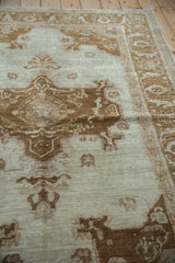 Angled view of the vintage Oushak rug showing the even wear and texture of its low pile.