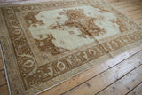 Distressed Oushak rug with a brown medallion and border, viewed from a high angle.
