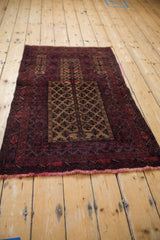Vintage Belouch rug corner showing pale raspberry red fringe and geometric wave gul borders.