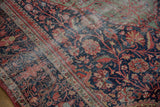 Navy field of an antique Farahan Sarouk rug, showing scrolling vinery, varied reds, and wear.