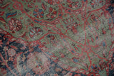 Worn pile texture of an antique Persian Farahan Sarouk rug, featuring green, red, and navy floral patterns.
