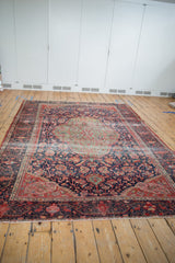 Antique Farahan Sarouk rug detail: navy field, scrolling tendrils, floral motifs, time-softened hues.