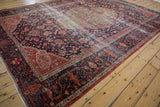 Antique Farahan Sarouk rug corner featuring navy blue field, tomato red border, and floral tendrils with soft patina.