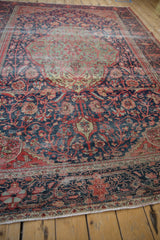 Antique Farahan Sarouk carpet's worn navy and red floral border and fringe.