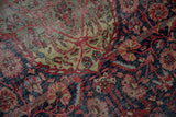 Detail of antique Farahan Sarouk rug with prominent wear, scrolling vinery, and rich floral patterns.