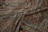 Worn texture and henna motif visible on a folded distressed Mahal carpet.