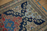 Vintage Persian rug's shield medallion with starbursts and checkered blossoms in navy, red, beige.