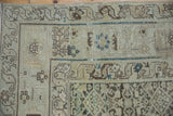 Corner detail of a distressed Hamadan rug with a serpent dragon style border in muted tones.